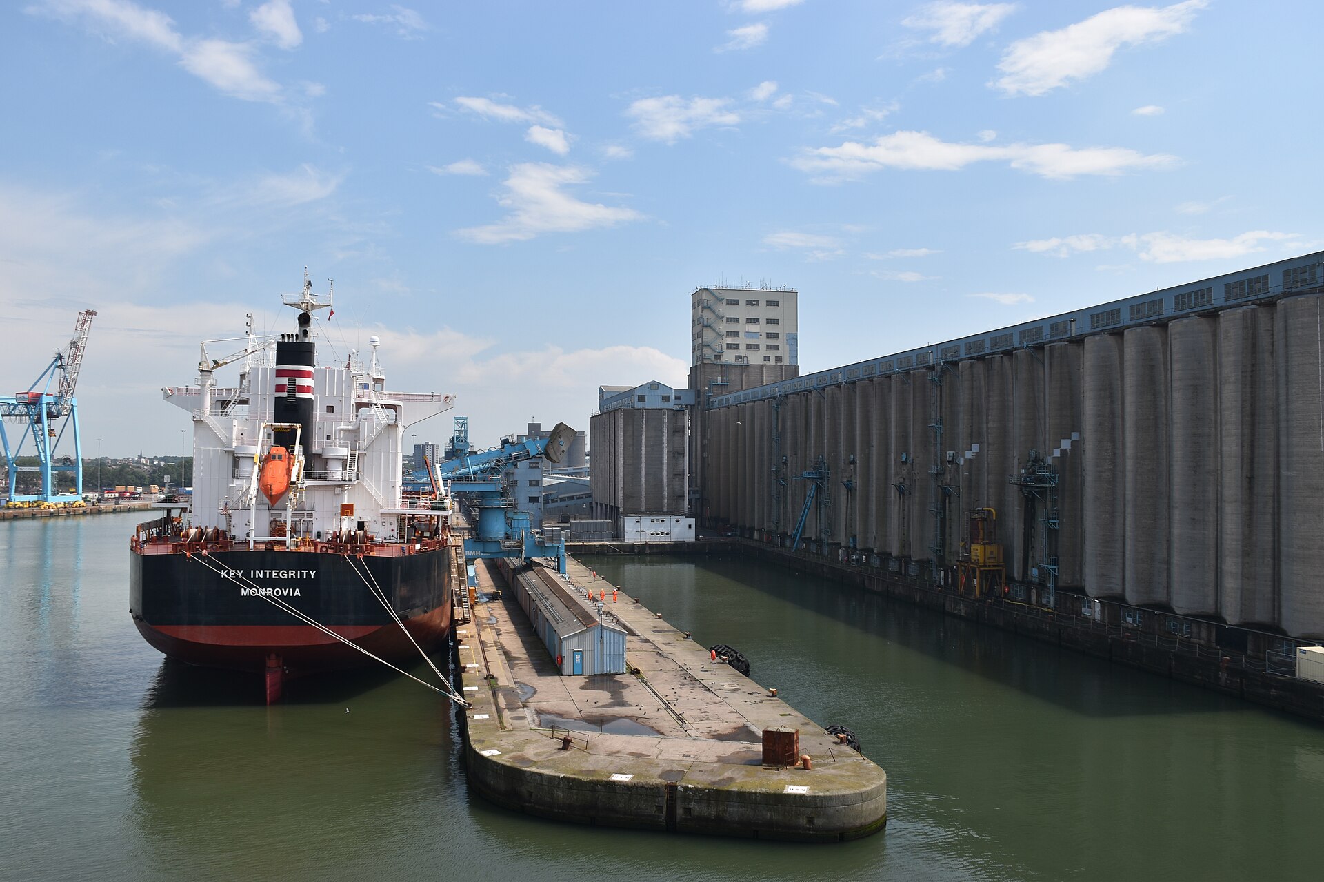 A bulk carrier berthed at the Seaforth grain terminal in Liverpool, with silos and conveyors along the dock.